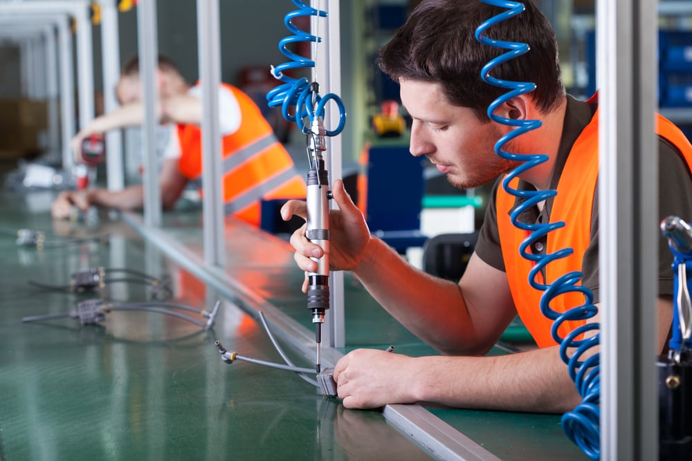 Men during precision work on production line, horizontal Men during precision work on production line, horizontal